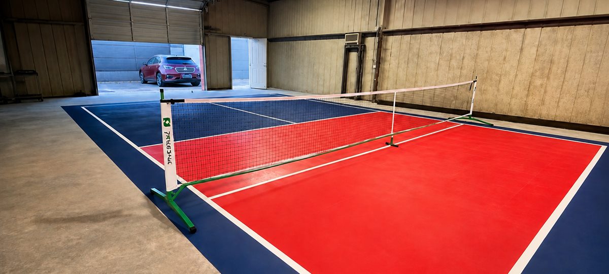 Red and blue acrylic pickleball court flooring inside a workshop